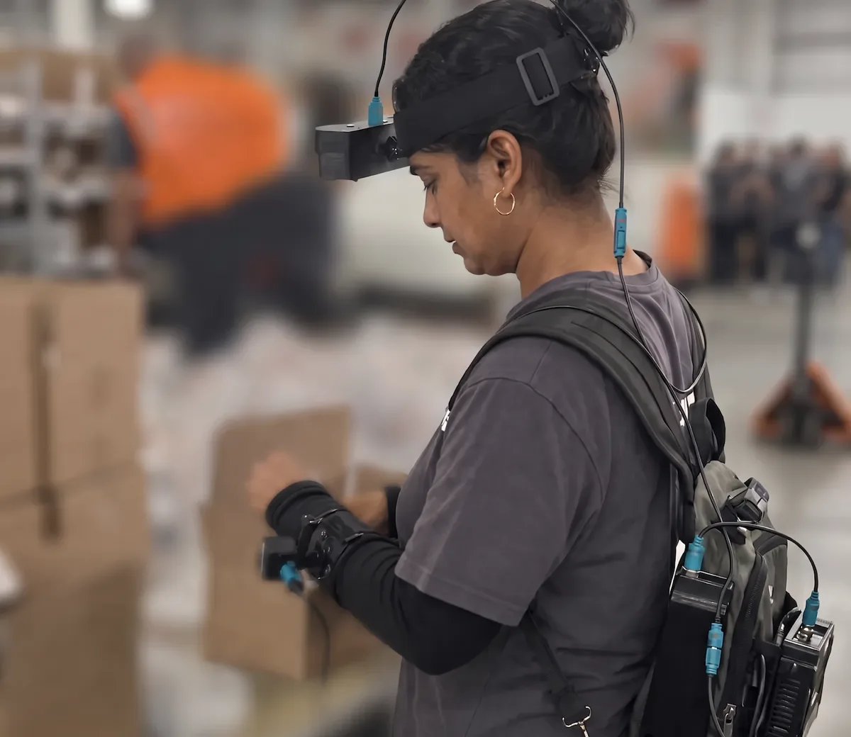 Field capture operator with head stereo rig, wrist camera, and backpack logging unit in a partner warehouse